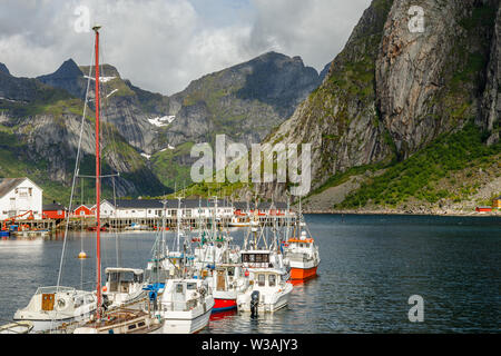 Yachts and boats with mountains in the background at pier in Reine, Moskenesoya, Lototen islands,, Nordland County, Norway Stock Photo