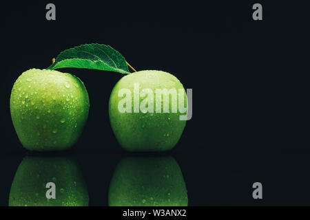Two green apples on a black glass table background. Stock Photo