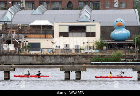 Berlin, Germany. 14th July, 2019. Paddle boats pass by an oversized duck on the Spree. Credit: Soeren Stache/dpa/Alamy Live News Stock Photo