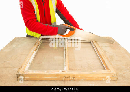 Carpenter using a handsaw while repairing and restoring an old window frame sash. Sash window restoration. Stock Photo