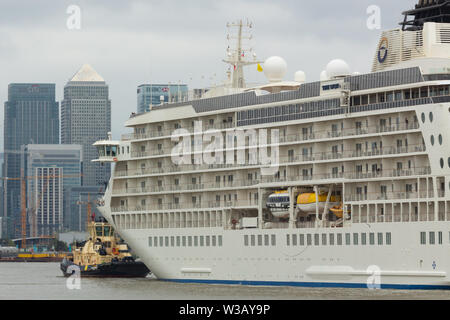 London, UK. 14th July, 2019. The World passes through the Thames Barrier and approaches Canary Wharf. Luxury ship The World has arrived in London and moored at Greenwich. The 196m long ship is the largest privately owned residential yacht in the world with 165 residences aboard, all owned by the ship's residents. Passengers live aboard the ship as it cruises the world. Credit: Rob Powell/Alamy Live News Stock Photo