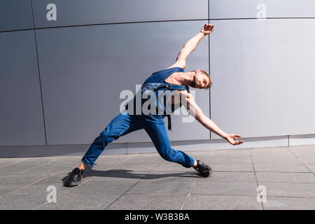 Young man dancing on street with arms outstretched Stock Photo