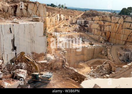 OROSEI, ITALY - June 14, 2019: Excavator works in a quarry, moving large slabs of marble. Stock Photo