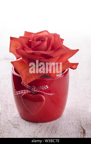 red bowl with heart and red rose on light wooden background Stock Photo