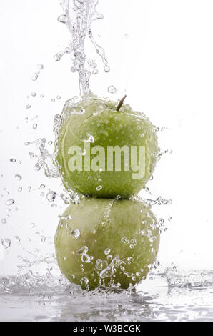 a wave of clear water falls on the green apple on a white background Stock Photo