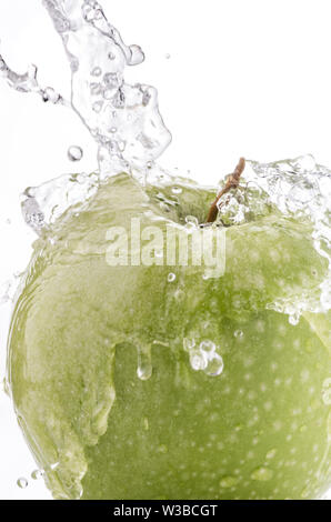 a wave of clear water falls on the green apple on a white background Stock Photo