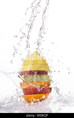 a wave of clear water falls on the sliced and varied fruit stacked on a white background Stock Photo