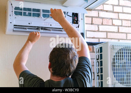 Male technician repairing air conditioner outdoors Stock Photo