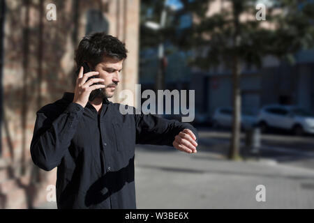 Young man making phone call walking on the street . Stock Photo