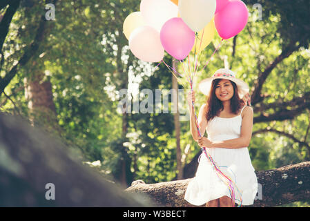 celebration and lifestyle concept - beautiful woman with colorful balloons outdoor in the park Stock Photo