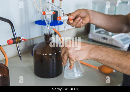 Man or male hold test tube in hands produces chemistry experiment test and research in modern chemistry lab. Stock Photo