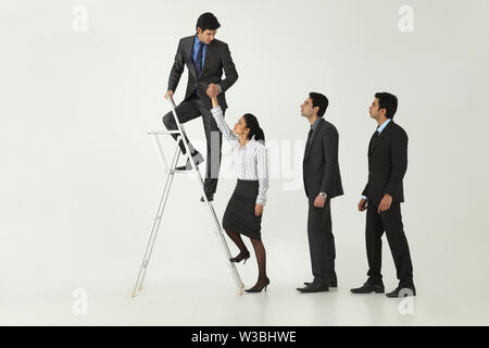 Businessman helping his colleagues to climbing step ladder Stock Photo