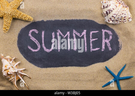 Handwritten chalk inscription SUMMER on blackboard, lying among the seashells and starfish on the sand. Top view Stock Photo
