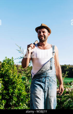 Smiling young farmer man standing in the garden while looking away Stock Photo