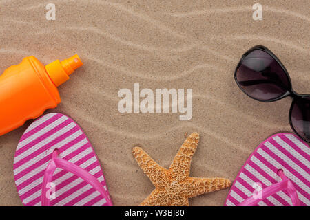 Beach accessories on sand. Flip flops and sunglasses. Top view. Stock Photo