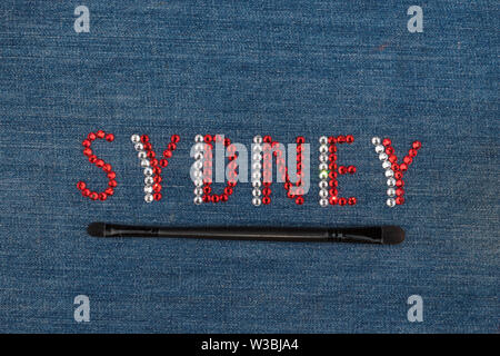 Inscription Sydney, inlaid rhinestones on denim. Top view. City of fashion, shopping, tourism. Stock Photo