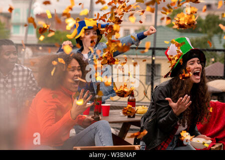 Multicultural female football fans throwing confetti while cheering Stock Photo