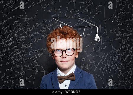 Little child boy thinking on blackboard background. Brainstorming and idea concept Stock Photo