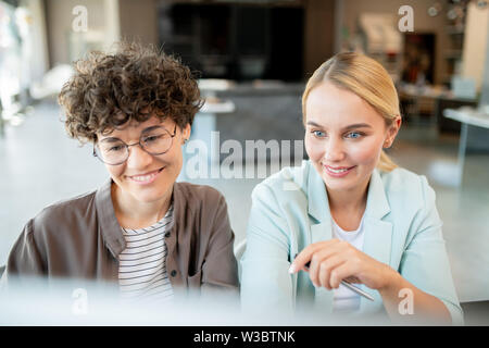 Two happy female students watching video conference Stock Photo