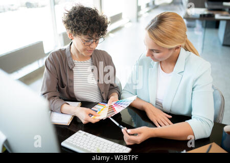 Young female designers consulting while working over new interior collection Stock Photo