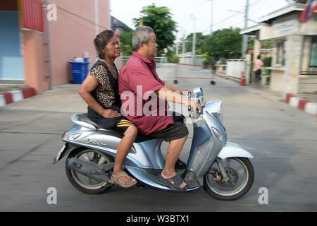 SAMUT PRAKAN, THAILAND, JUN 03 2019, Older couple rides in a motorbike. Scooter with pair on city street. Stock Photo