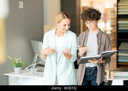 Two creative designers looking through catalogue of interior design Stock Photo