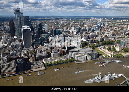 Aerial view of financial district skyscrapers on the muddy River Thames with Tower of London Castle and HMS Belfast warship London England