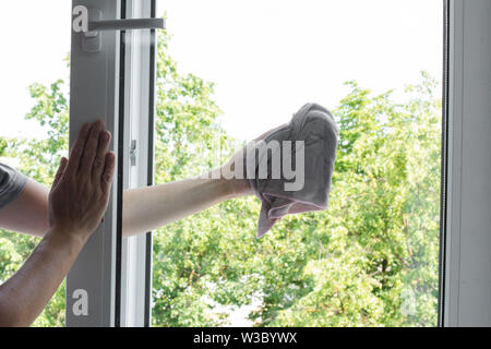 Male worker keeping rag in hand and wiping window Stock Photo