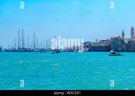 Acre, Israel - July 08, 2019: View of the sea wall and the fishing port, with locals and visitors, in the old city of Acre (Akko), Israel Stock Photo