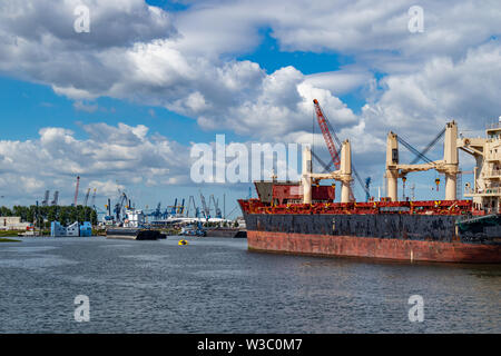 Logistics business. Ship anchored and huge cranes at harbor. International commercial port, city of Rotterdam background, sunny summer day Stock Photo