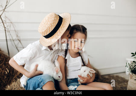 Brother and sister in hay hats keeping little chicks Stock Photo