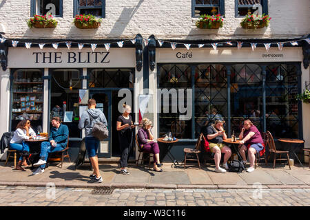 Customers enjoying summer sunshine alfresco outside The Blitz café  in Church Street Whitby  North Yorkshire England UK Stock Photo