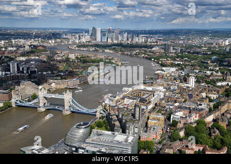 Aerial view of the muddy River Thames with Tower Bridge, modern curved City Hall and Canary Wharf skyscrapers in the distance London England