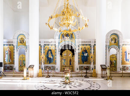 The nave of the Holy Trinity Cathedral of the Russian Orthodox Church in Paris is small with a chandelier and white walls adorned with golden frescoes Stock Photo