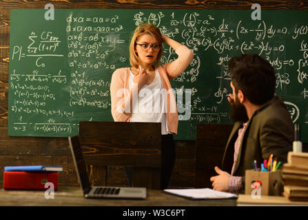 Attentive teacher talking to her student in science class at the university, Good teachers seek engaged students, Hipster is solving math exam, Modern Stock Photo