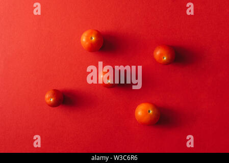 Five cherry tomatoes on a red background. Stock Photo