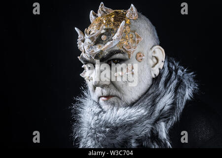 Stern demon with pale white skin tinted with gold. Evil creature controlling snow and frost, winter god. Monster with thorns on face wearing fur Stock Photo
