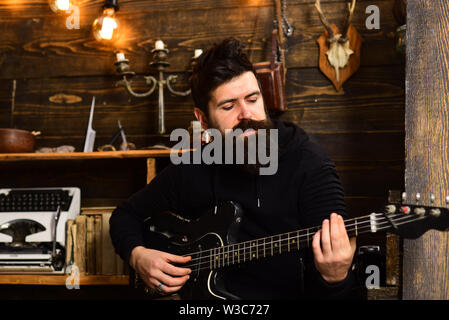 Man bearded musician enjoy evening rehearsing performance at home, wooden background. Boost your skills. Guy in cozy warm atmosphere learn new song Stock Photo