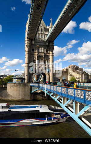 Tower Bridge across the Thames river in London with upper walkway and glass floor and boat passing under the bascule bridge