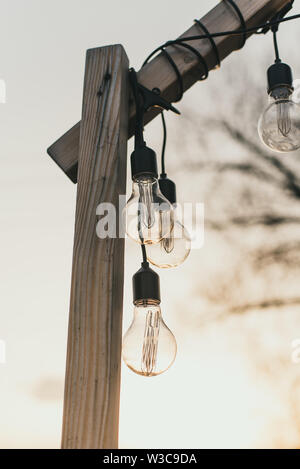 light bulbs in the street in daylight. A garland of light bulbs on a wooden pedestal in the afternoon in the sun outdoor. Stock Photo
