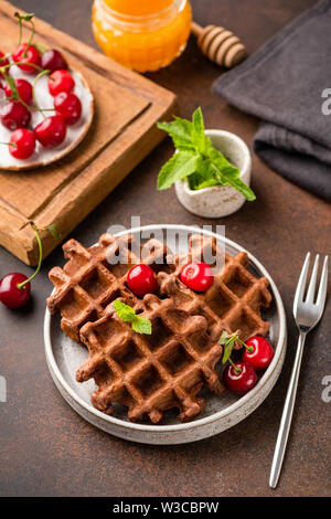 Whole wheat belgian waffles with sweet cherry and honey on plate, vertical orientation Stock Photo