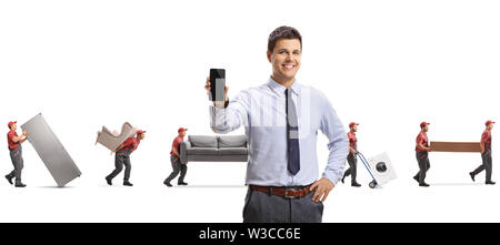 Male manager with a mobile phone and movers carrying furniture isolated on white background Stock Photo
