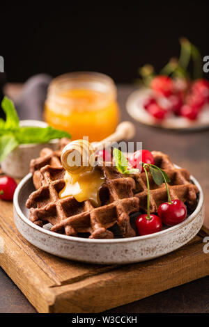 Belgian waffles with honey and sweet cherries. Tasty dessert. Healthy whole wheat waffles Stock Photo