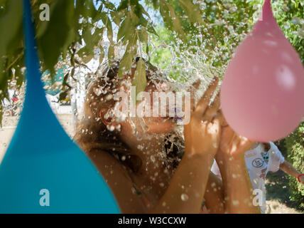 Odesa rgn. Ukraine, August 2, 2018: Splashes of water from a burst of a balloon on the face of a girl in a game at the summer camp Stock Photo