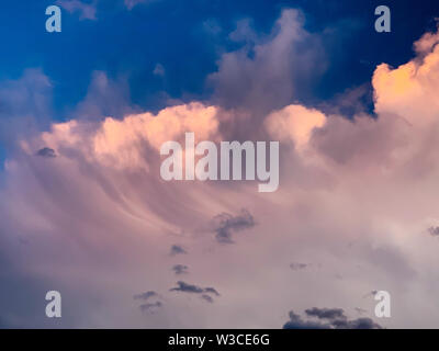 Dramatic evening sky with orange and dark storm clouds against the blue sky. Concept of upcoming storm and beautiful backdrop Stock Photo