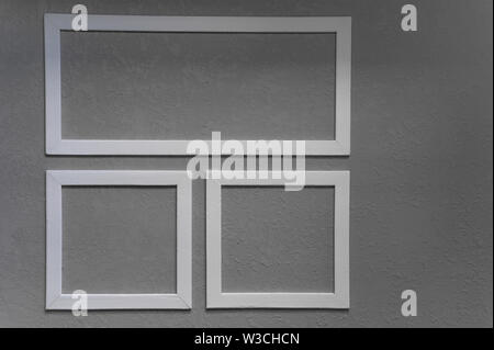Close-up of three white picture frames on grey wall background Stock Photo