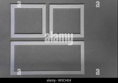 Close-up of three white picture frames on grey wall background Stock Photo