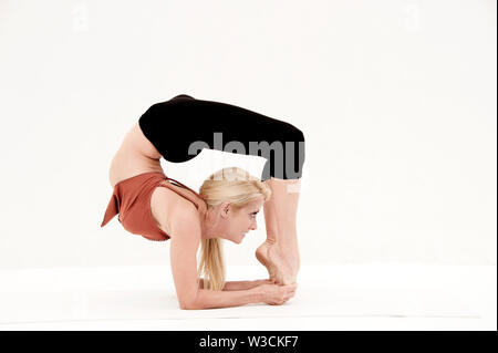 difficult advanced yoga pose by attractive female, on white background,  viewed from the front Stock Photo - Alamy