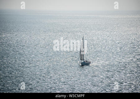 A lonely single sail boat in the Atlantic off the coast of Lisbon, Portugal. Stock Photo