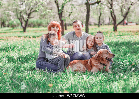 parents, children and their pet sitting on the lawn on a summer day. the concept of a healthy lifestyle Stock Photo